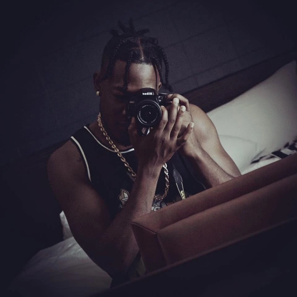 Mychael Harris holding a Nikon camera in a dark room.
